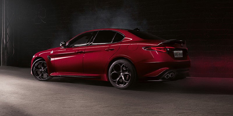 Rear three-quarter view of a red Alfa Romeo Giulia in a garage