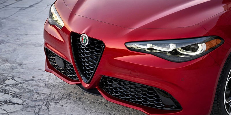 Close-up of a red Alfa Romeo's front grille and LED headlight