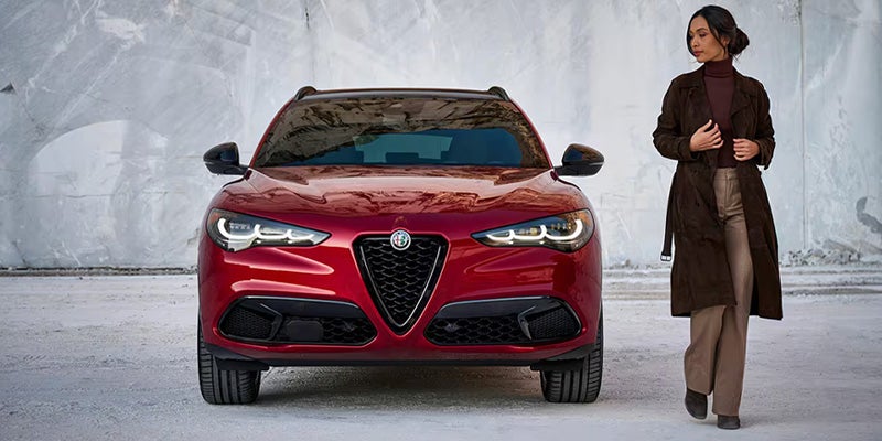 Front view of a red Alfa Romeo Stelvio SUV beside a person.