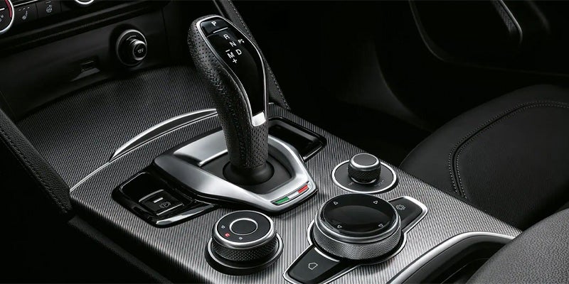Center console of an Alfa Romeo featuring gear shifter and rotary dial.