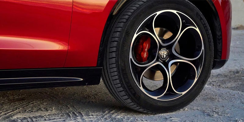 Red Alfa Romeo Stelvio wheel with five-hole design and red brake calipers.