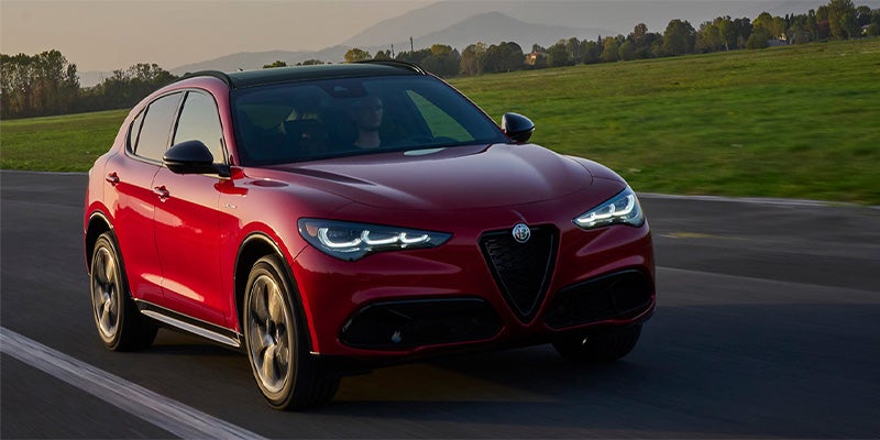 Front view of a red Alfa Romeo Stelvio driving on a road.
