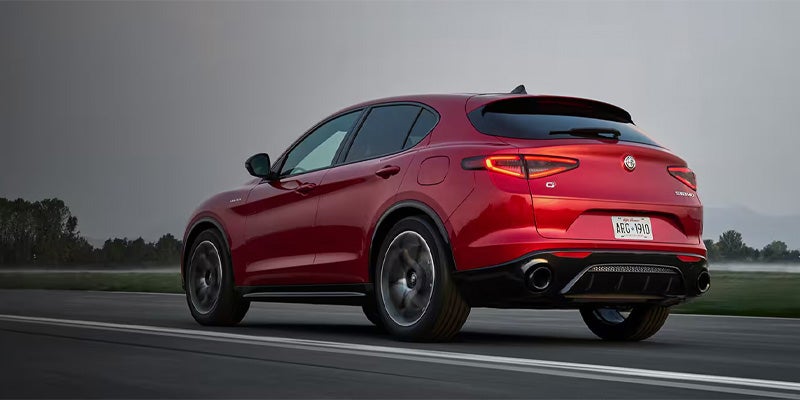 A red Alfa Romeo Stelvio SUV driving on a paved road