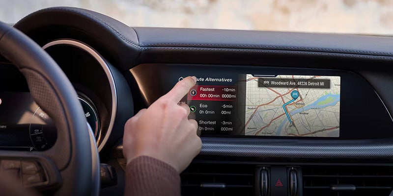 Hand interacting with the digital infotainment navigation screen in the dashboard
