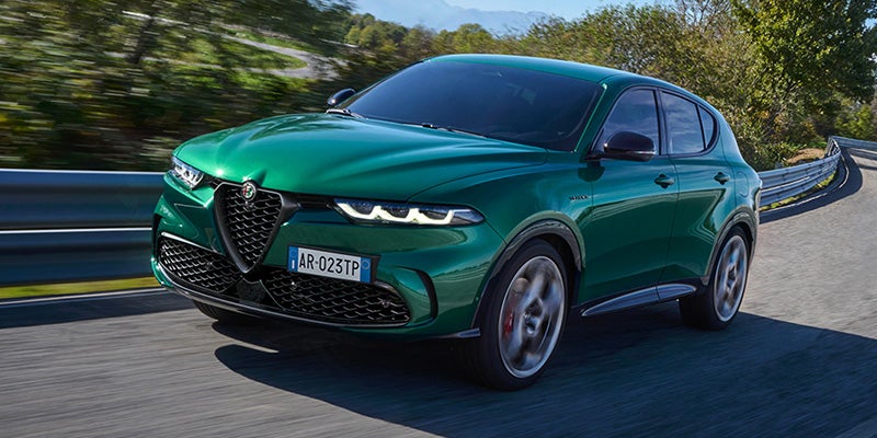 Front three-quarter view of a green Alfa Romeo Tonale driving on road.