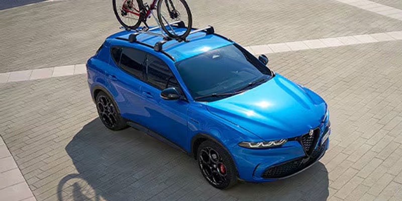 High-angle view of a blue Alfa Romeo Tonale with a roof-mounted bike.